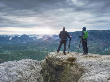 Tourist couple on the top of rocky mountain. Friends in nature.