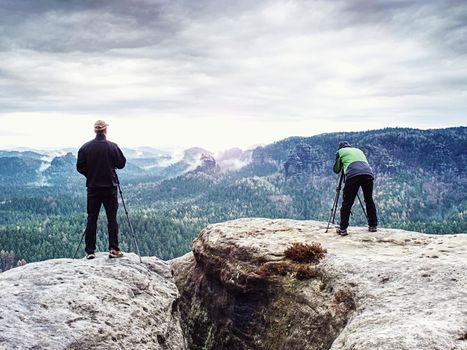 Outdoor shot of talented hobby photographers taking pictures  in rocks.  Camp, adventure, trip and traveling concept.