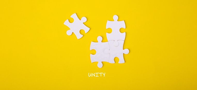 Four puzzle pieces connected to each other with the word unity. Unity, synergy, integration or solidarity concept.