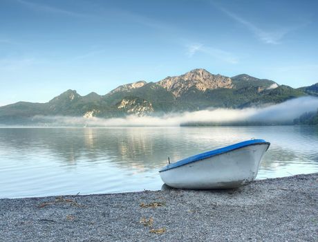 Little boat on lake shore, beautiful summer nature. Mountain lake