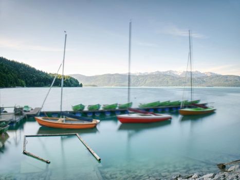 Sports boats, blue green mountain lake, windless summer day. 