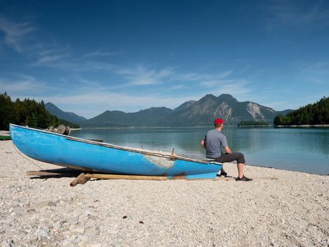 Fishing boat on shore on background of picturesque landscape of lake and green nature around in bright sunny summer day.