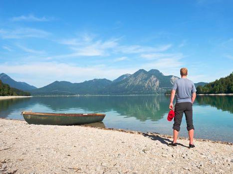 Modern sport fishing paddle boat anchored on shore of the lake bay. Peaceful level of lake. Windless sunny day.
