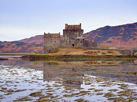 Tides in the lake at Eilean Donan Castle, Scotland. The popular stony bridge over the remnants of water with massive tufts of water algae. Poor light with low cloud.