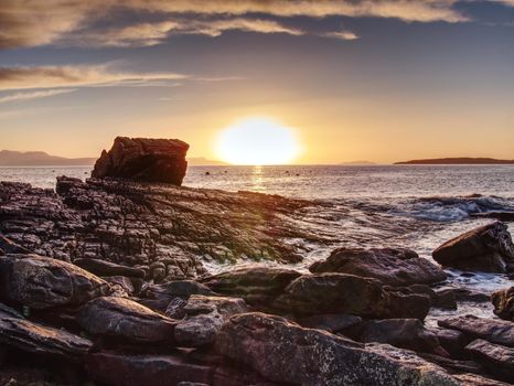 Peaceful dawn at Elgol bay. Low angle  overlooking of offshore rocks and smooth sea, mountains at horizon. Winter  Isle of Skye, Scotland 