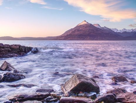 Evening rocky shore with sea water and large cracked rocks with erosion marks.  Rocky coastline with sea water.

