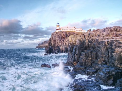 Lighthouse building with tower against to evening sky. Popular Neist Point, spit of land Isle of Skye, Scotland