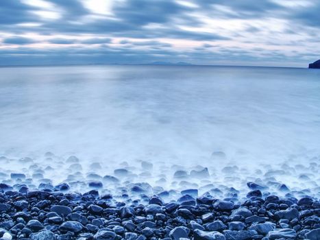 Blue sunset at rocky coast of sea. Slow shutter speed for smooth water level and dreamy effect