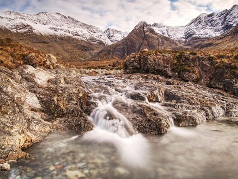 Waterfall and rapids against to scenic snowy mountain landscape, Isle of Skye, Scotland