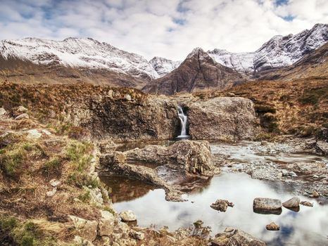 Multiple waterfalls, seemingly vibrant blue and  green in color, with cold swimmable pools. Popolar trek at Glenbrittle, Isle of Skye, Scotlland