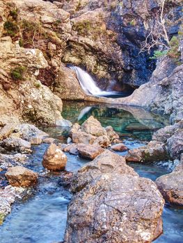 Blue water of river Brittle in trail known as Fairy pools. The mountain river cut in soft rocks colorful pools.  Bellow the mountains of Glenbrittle on Isle of Skye Scotland