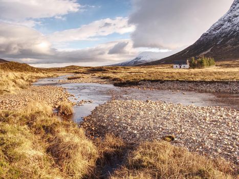 River at base of snowy mountains in Scottish Highlands near Glencoe  in winter. Cold windless winter morning