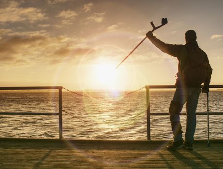 Tourist on ferry boat mole within sunrise or sunset. Warm colors, reflection of Sun in camera lens. 