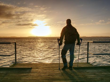 Tourist on ferry boat mole within sunrise or sunset. Warm colors, reflection of Sun in camera lens. 