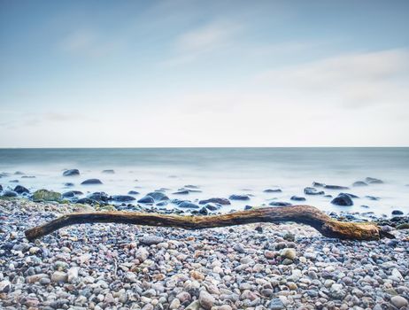 Moody seascape - storm on the sea, turquoise waves breaking on coastal cliffs against cloudy sky. Rocks at water. 