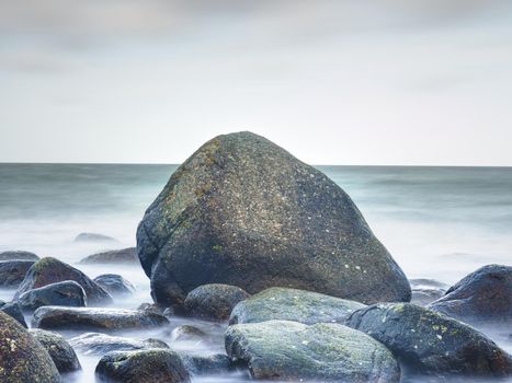 Coast of the sea, ocean. Stones on the shoreline. Blue silent water