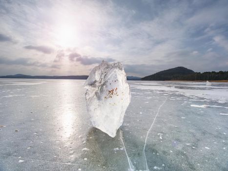 Ice breaking. Floe on frozen lake with sunset sky background,