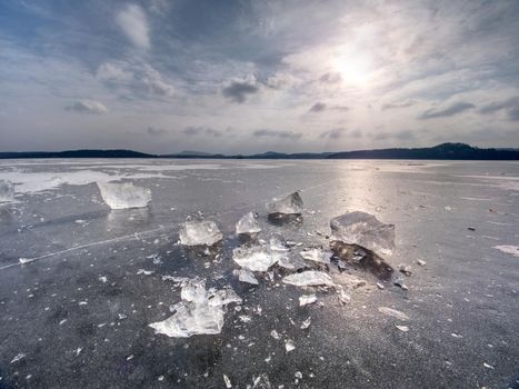 Ice breaking. Floe on frozen lake with sunset sky background,