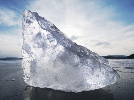 Abstract ice floe on frozen lake, texture of weathered ice and sparkling of evening sun. Deep ice cracks.