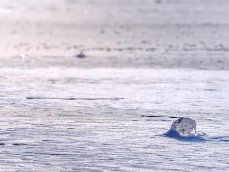 Transparent ice block on  frozen sea surface. Amazing Sun  reflection in scratches and cracks. Winter season