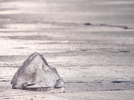 Arctic cold landscape of icy lake at sunset with cracks and patterns on the ice. Winter landscape 