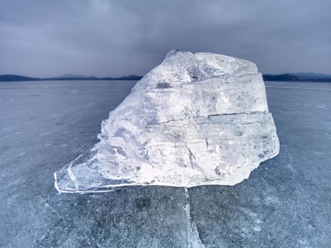 Ice floe and crushed ice on dark frozen and flat  ground. Shining crushed ice in strong colorful backlight.