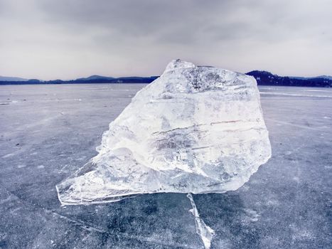 Arctic ice. A large piece of natural ice on a green blue flat ice of frozen lake, water bubbles texture. Shiny detail inside wonderful of transparent. stalactite ice.