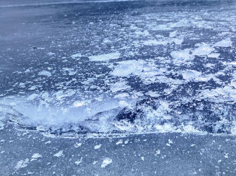 Ice floe and crushed ice on dark frozen and flat  ground. Shining crushed ice in strong colorful backlight.