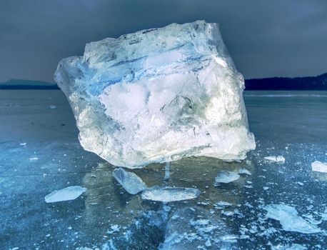 Icy winter landscape - thick ice covered ashore. Crashed ice floe on frozen  sea in within sunset