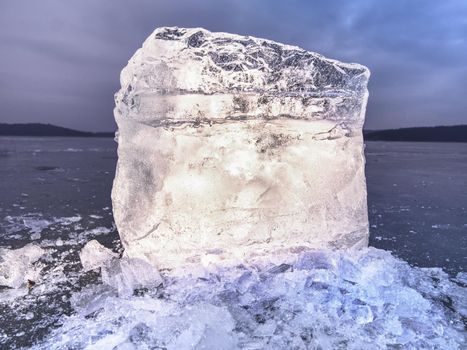 Icy winter landscape - thick ice covered ashore. Crashed ice floe on frozen  sea in within sunset