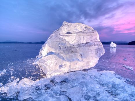 Detail view into  an ice with deep scratches and cracks. Cut floe against to evening sky and spot light.