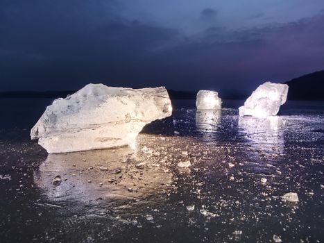 Detail view into  an ice with deep scratches and cracks. Cut floe against to evening sky and spot light.