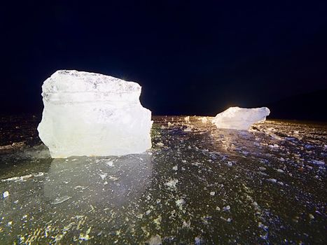 Icy winter landscape - thick ice covered ashore. Crashed ice floe on frozen  sea in within sunset