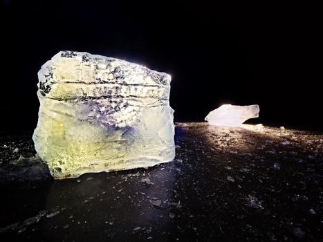 Ice floe and crushed ice on dark frozen and flat  ground. Shining crushed ice in strong colorful backlight.