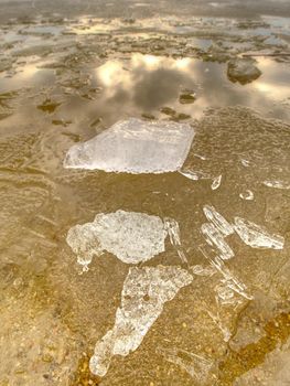 Winter natural wonder. Yellow pieces of snow melting on beach. Wonderful nature creation.