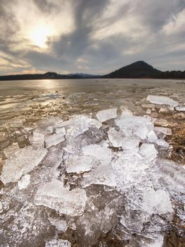 Pieces of clear natural ice on frozen lake,  very close up view. Early mealting of ice, ecology problem.