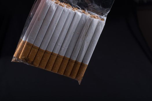 Pack of cigarette hanging on black background