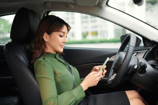 Young woman driving a car looking at the phone screen