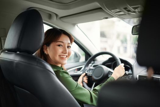 Confident and beautiful. Rear view of attractive young woman in casual wear looking over her shoulder while driving a car