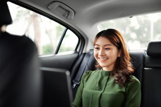 Beautiful young business woman is using laptop in the car to work