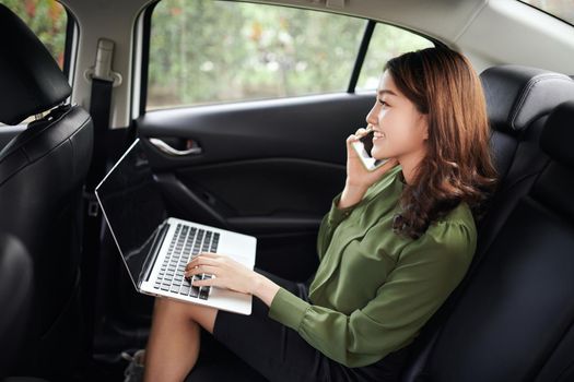 Executive businesswoman in car work on her laptop.