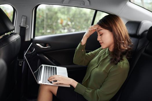 Asian woman bored stress work using laptop computer while sitting in her car