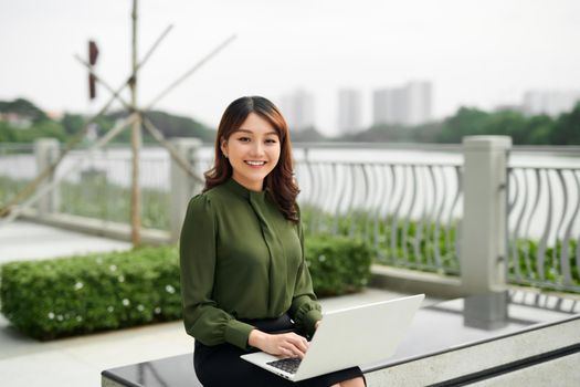 Young business woman using laptop sitting in the park.