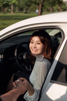 Young smiling woman getting keys of a new car. Concept for car rental