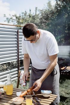 Backyard barbecue. Mans hands grilling kebab and vegetables on metal skewers.