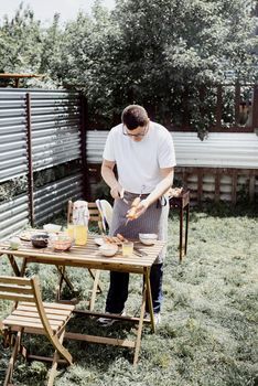 Backyard barbecue. Mans hands grilling kebab and vegetables on metal skewers.