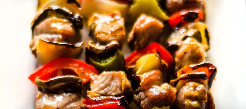 grilled skewers of meat and vegetables on a wooden board, colorful and tasty dish