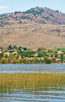 Warm summer evening on Osoyoos lake. Overview of farm lands and resorts on mountains and sky background