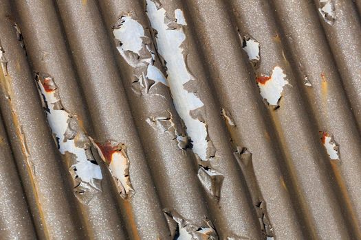 Photograph of brown paint peeling off a corrugated iron roof due to exposure to the environment