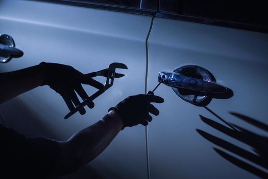 Car thief using a tool to break into a car